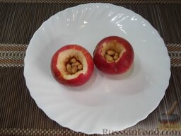 Запеченные яблоки с орехами и виноградом: Положите арахис в каждое яблоко.