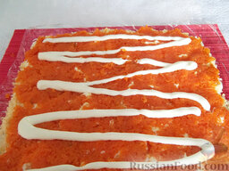 Салат рулетом: Отварную морковь очистите, натрите, выложите на сыр и полейте майонезом, который аккуратно размажьте по всей поверхности.