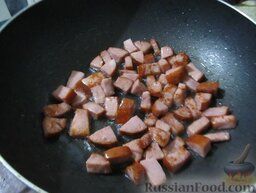 Рис с жареной колбасой и яйцами: Вок разогреть на плите, добавить столовую ложку растительного масла. Обжарить в воке колбасу до коричневого цвета.