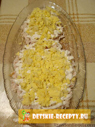 Новогодний салат «Снеговик»: 4. Желток куриного яйца — раскрошенный руками либо натертый на крупной терке.