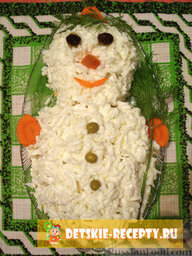 Новогодний салат «Снеговик»: Теперь натертый на крупной терке белок и украшение: пуговички — консервированный горошек, глазки — изюм, носик, ротик и ручки с шапочкой — отварная яркая морковь. Да, не забудьте дать снеговику метлу из веточки укропа и из него же сделать симпатичную челочку. Салат снеговик готов, приятного аппетита!