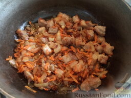 Капуста тушеная с мясом и черносливом: Разогреть казанок, добавить растительное масло или смалец. Выложить мясо. Обжарить на среднем огне, помешивая, до золотистости (12-15 минут). Затем добавить лук и морковь. Тушить все вместе, помешивая, 5-7 минут.