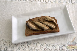 Бутерброды со шпротами: Выкладываем на ржаные кусочки хлеба рыбу (2-3 шт.).