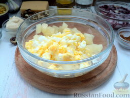 Салат с курицей и ананасом: Переложите ананас в глубокую емкость, добавьте измельченные вареные яйца.