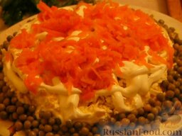 Салат «Полянка»: Последний слой салата -натёртая морковь. Украшаем салат горошком по кругу.
