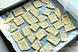 Соленые крекеры с кунжутом: Перекладываем соленые крекеры с кунжутом на противень, который рекомендуется застелить кулинарным пергаментом.