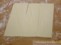 Круассаны с шоколадом: Расстелите тесто на присыпанном мукой столе. Нарежьте пласт теста треугольниками. Размер выбирайте сами, у меня ширина широкой части - 8 см.