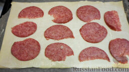 Пицца из слоеного теста, с курицей и грибами: Разложите по поверхности кусочки тонко нарезанной колбасы.