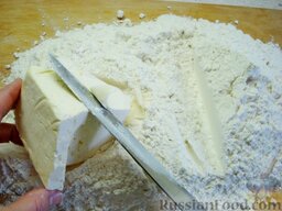 Торт "Наполеон": На разделочную поверхность просеять всю муку. Замерзший маргарин нарезать ножом на тонкие щепки, перемешивая их сразу же с мукой.