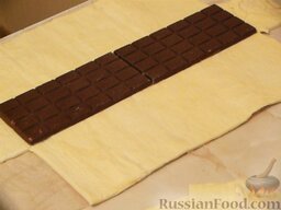 Рулет из слоеного теста, с шоколадом и орехами: Плитку шоколада выкладываем точно посередине слоеного теста. Вырезаем углы теста (см. на фото и видео).