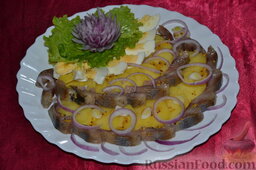 Салат "Русский" с сельдью: Отварной картофель очищаем, нарезаем.   Выкладываем в тарелку картофель, солим его. Выкладываем кусочки филе селёдки, ломтики вареных куриных яиц, кольца лука.   Заправляем салат 