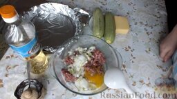 Кабачки, запеченные с фаршем и сыром: Подготовить ингредиенты для кабачков, запеченных с фаршем и сыром.   Лук почистить, помыть и мелко нарезать.   В глубокую емкость поместить мясной фарш, добавить лук и яйцо.