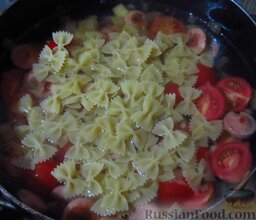 Макароны с сосисками, запеченные в сливках, с сыром: Залейте сосиски с помидорами водой, чтобы ее уровень был выше содержимого сковороды примерно на 3 см. Доведите до кипения, высыпьте макароны, посолите, накройте крышкой, готовьте до полуготовности.