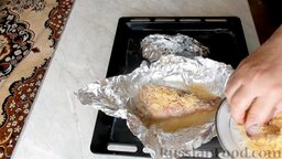 Морской окунь, фаршированный грибами, в фольге: Спустя 30 минут достать противень из духовки. Развернуть фольгу и посыпать морского окуня тертым сыром.