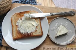 Тосты по-французски с голубикой: Поверх сахара намазываем творожный сыр, распределяя его на неостывшем хлебе равномерным слоем.