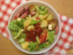 Теплый салат с картофелем: Заправьте салат кетчупом, посолите и поперчите по вкусу,  аккуратно перемешайте все ингредиенты.  Теплый салат из картофеля с сосисками и овощами готов.