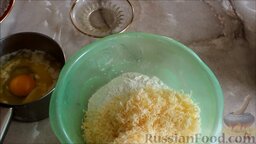 Суп с фрикадельками и сырными шариками (клецками): Тёртый сыр высыпать в миску с мукой. Яйцо разбить в ёмкость с растопленным сливочным маслом и взбить до однородной консистенции.