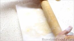 Торт "Медовик": Выложить один кусочек теста на присыпанный мукой пергаментный лист, накрыть второй частью листа и раскатать скалкой.