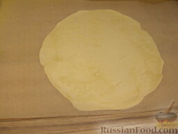 Торт слоеный «Наполеон»: Включить духовку.  Тесто вынимать из холодильника по одному куску. Работать с тестом нужно сразу на пекарской бумаге (или на фольге), на которой корж будет выпекаться. Раскатывать его в тонкий пласт (0,3-0,5 см) нужной для торта величины, примерно 25 см в диаметре.
