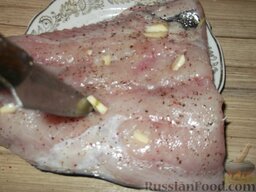 Толстолобик, запеченный по-домашнему: Чеснок очистить и нарезать. Рыбу нашпиговать чесноком. Для этого сделать проколы ножом до самой кожи. В каждый прокол вставить кусочек чеснока.