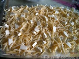Запеканка из риса и мясного фарша с яблоками: Разровнять поверхность риса, посыпать тертым сыром, разложить сверху кусочки масла.