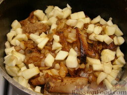 Тушеные свиные ребрышки: Через 25-30 минут после начала варки в чугунок добавить обжаренный лук и нарезанное очищенное яблоко.